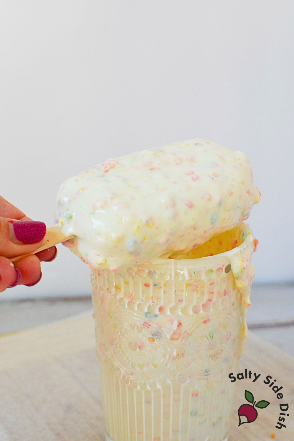 Fruity pebbles cake pop coated in white chocolate with coating dripping down