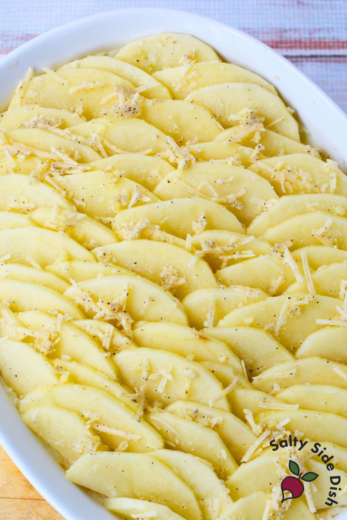 Close up of sliced potato layers on top of mashed potatoes before baking