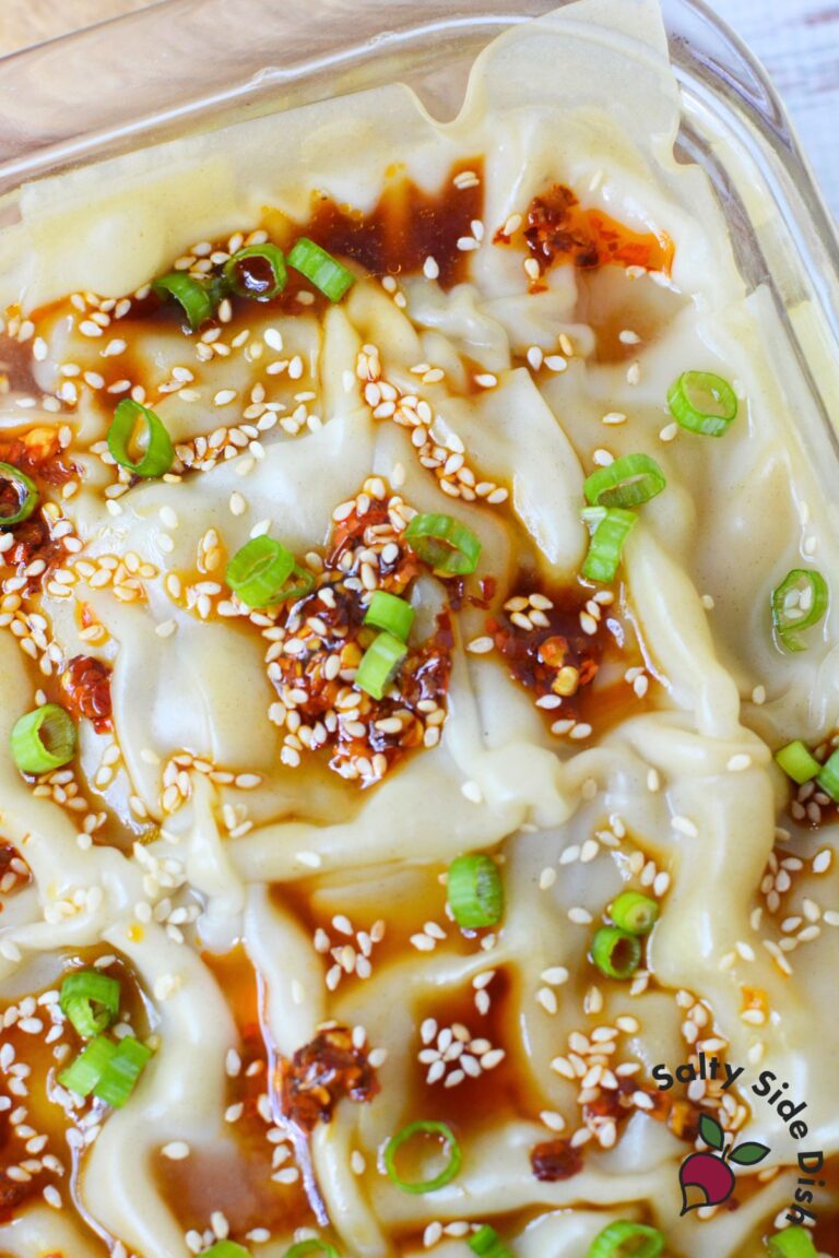 Close-up of finished dumpling lasagna topped with soy sauce, chili oil, sesame seeds, and green onions.
