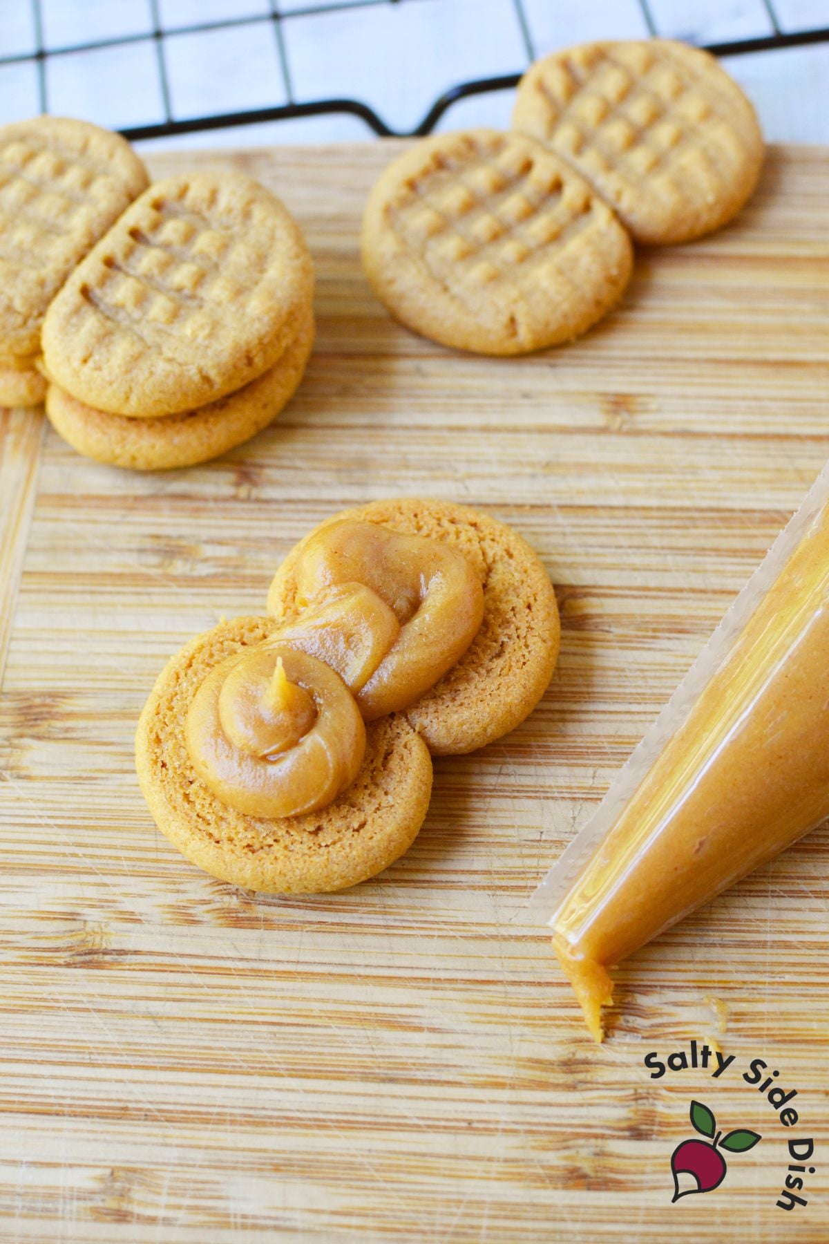 Piping peanut butter filling onto a cookie to assemble homemade Nutter Butters