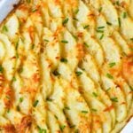 Baked potato gratin with browned cheese and chives in a white dish