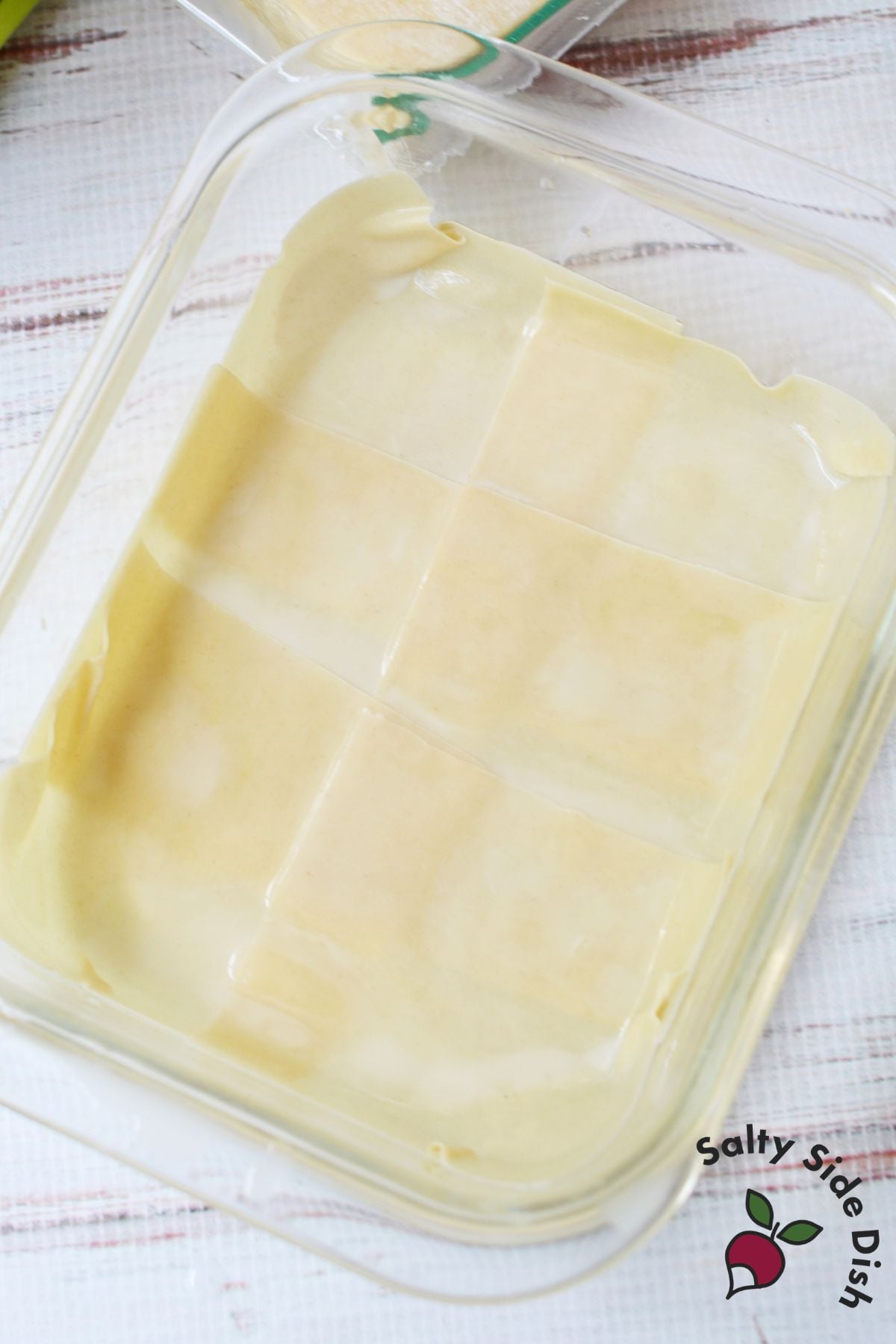 Wonton wrappers arranged in overlapping layers inside a glass baking dish.