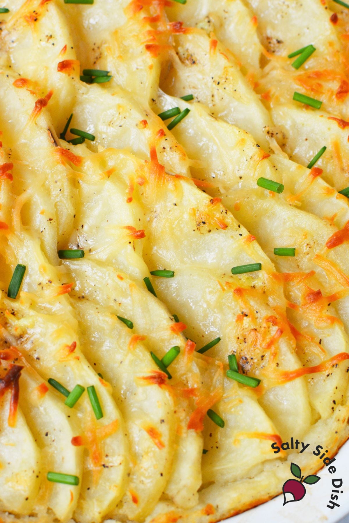 Baked mashed potato gratin topped with melted cheese and fresh chives