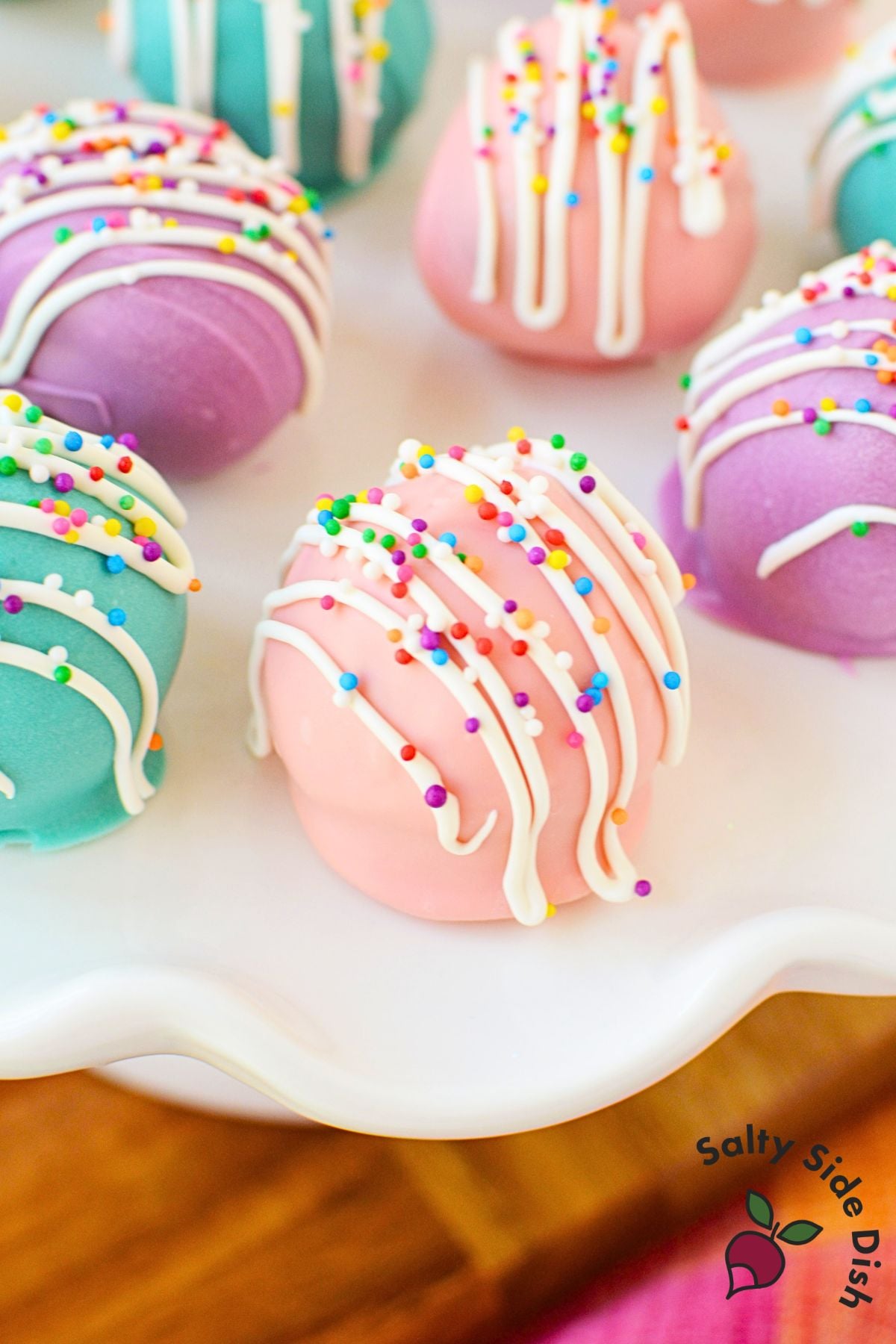 Colorful Spring Oreo Truffles decorated with white drizzle and rainbow sprinkles on a serving platter.