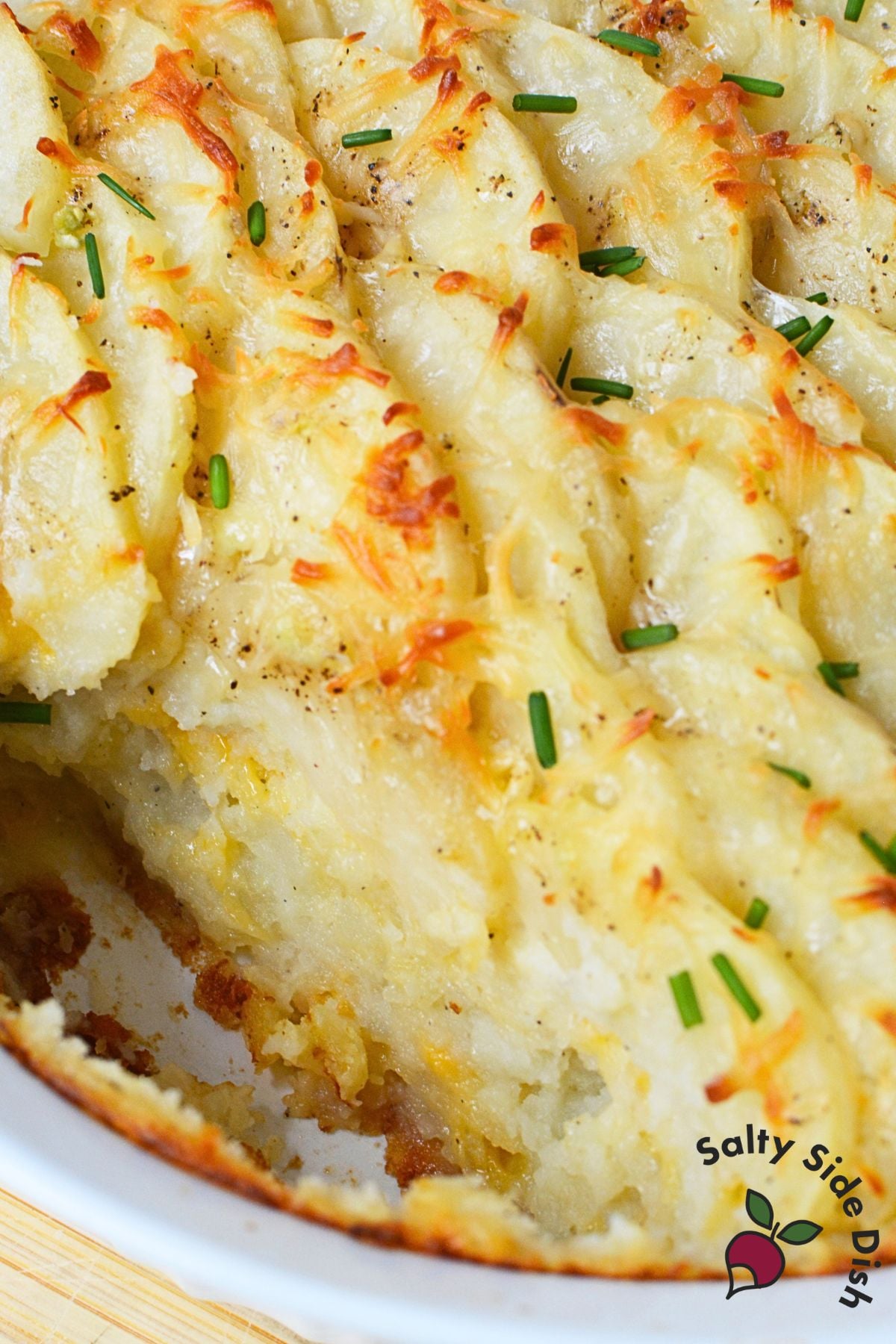 Close up of golden baked potato gratin with cheese and chives