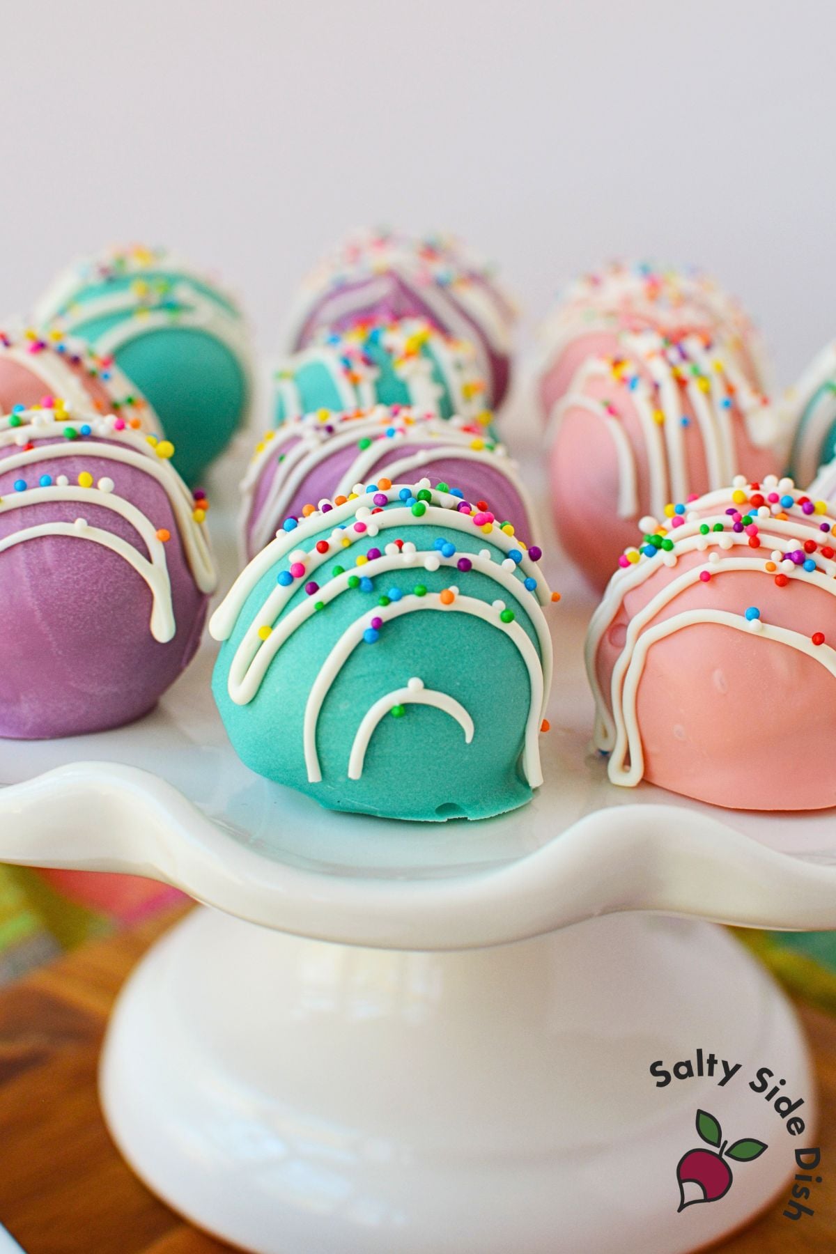 Colorful Spring Oreo Truffles decorated with white drizzle and rainbow sprinkles on a serving platter.