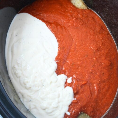 Alfredo and marinara sauce added to chicken in a slow cooker