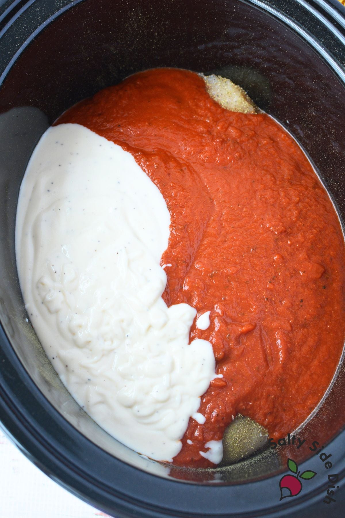 Alfredo and marinara sauce added to chicken in a slow cooker