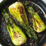 Sautéed baby bok choy with garlic, sesame seeds, and crushed red pepper in a skillet
