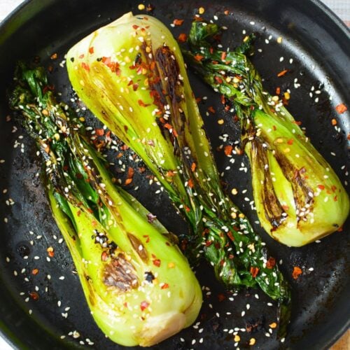Sautéed baby bok choy with garlic, sesame seeds, and crushed red pepper in a skillet