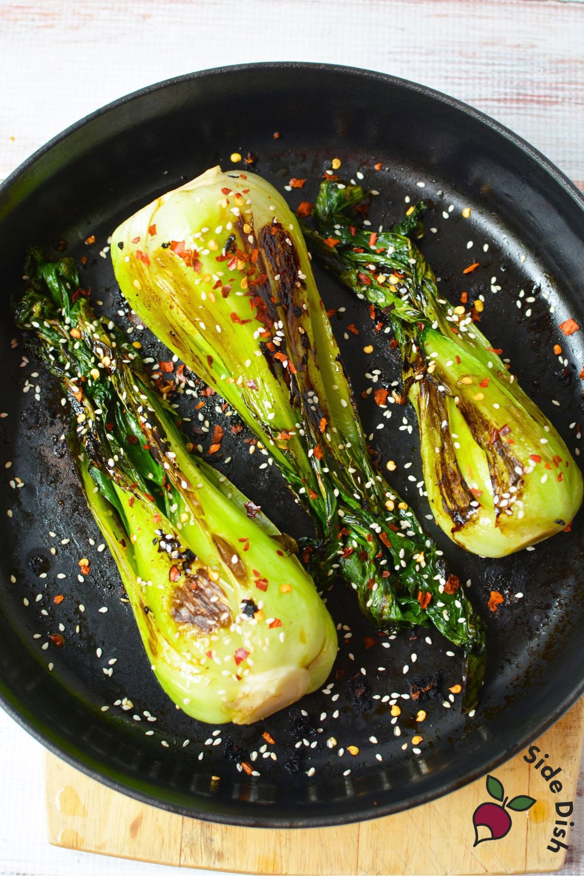 Sautéed baby bok choy with garlic, sesame seeds, and crushed red pepper in a skillet