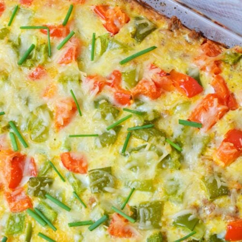 Close up of baked breakfast potato casserole with melted cheese, bell peppers and chives