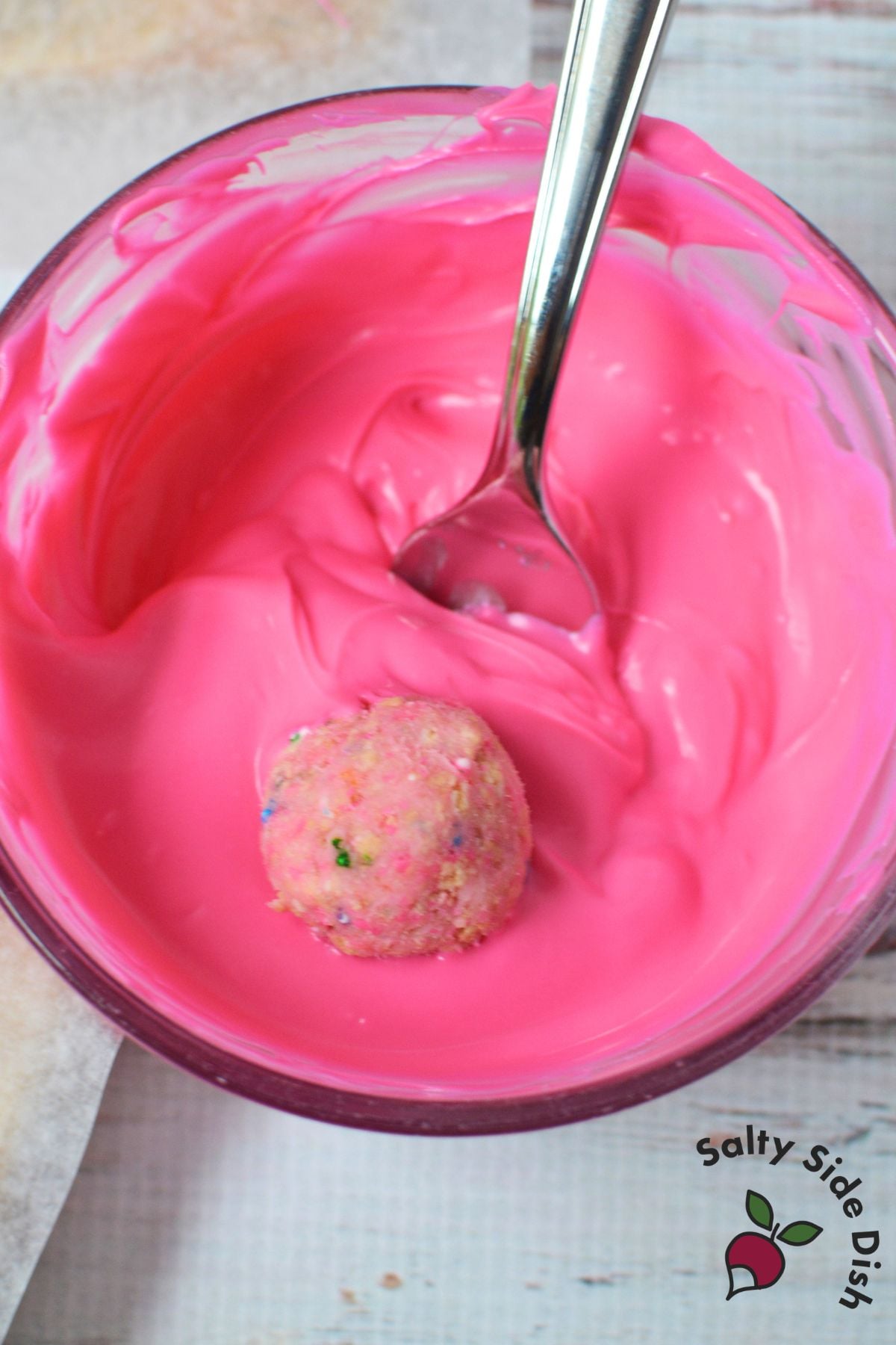 Circus Animal Cookie truffle being dipped into melted pink candy coating