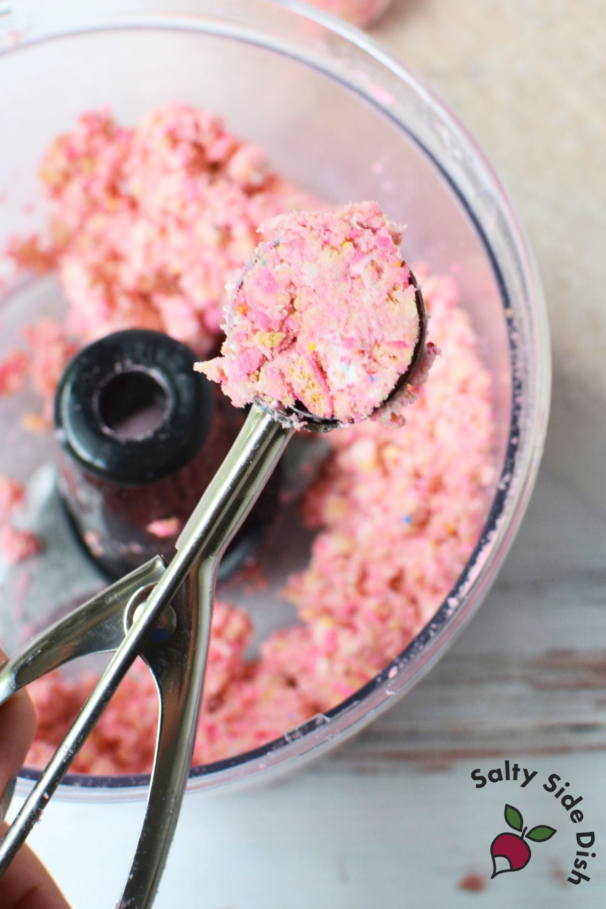 Circus Animal Cookie truffle being dipped into melted pink candy coating
