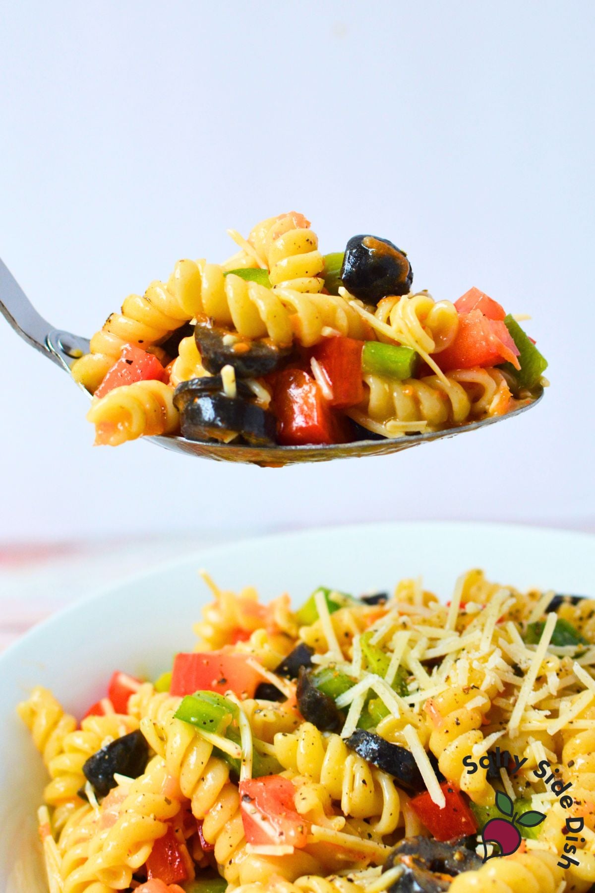 Spoonful of Olive Garden pasta salad with rotini, bell peppers, black olives, and Parmesan cheese