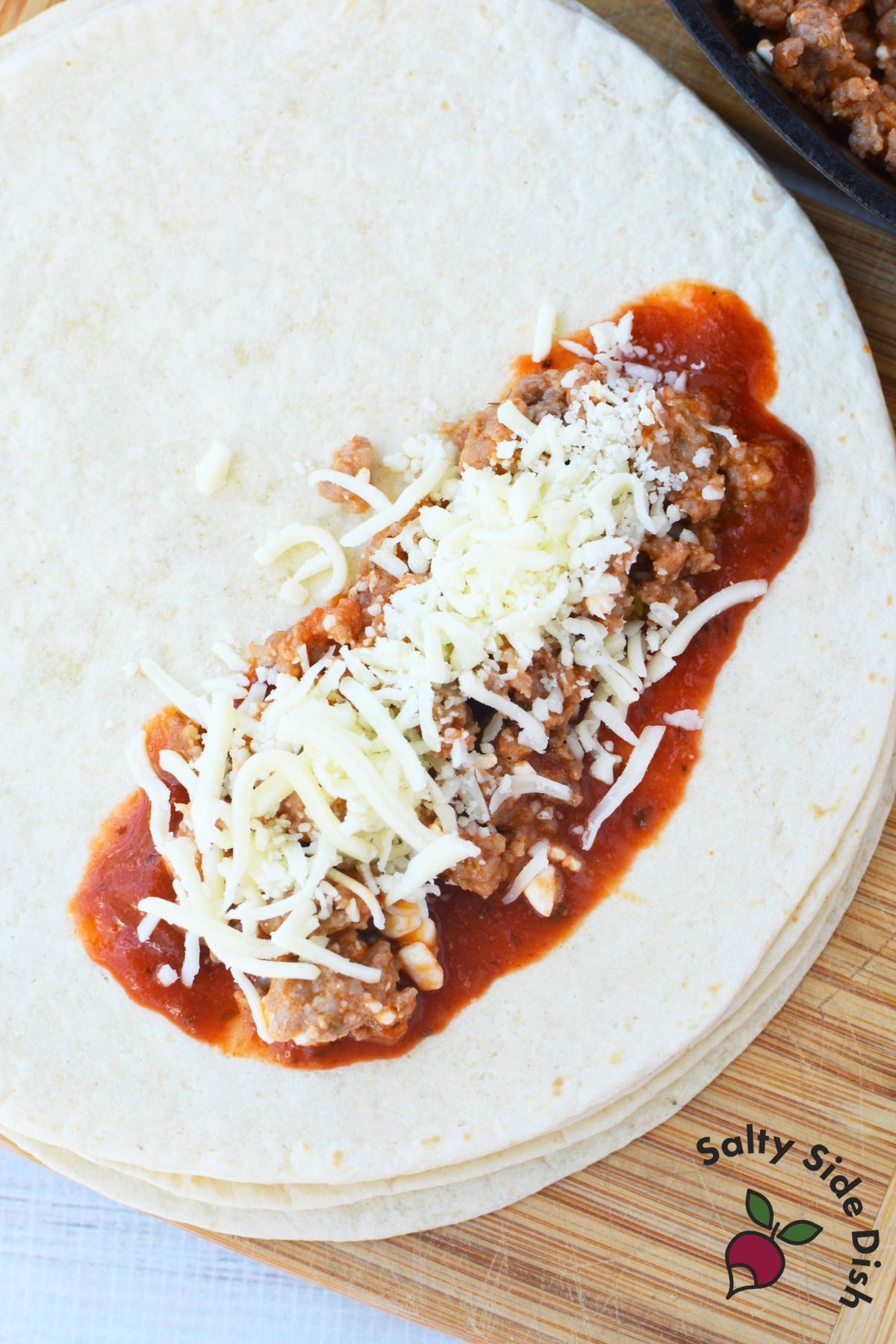 Flour tortilla topped with pasta sauce, Italian sausage filling, and mozzarella for lasagna rolls