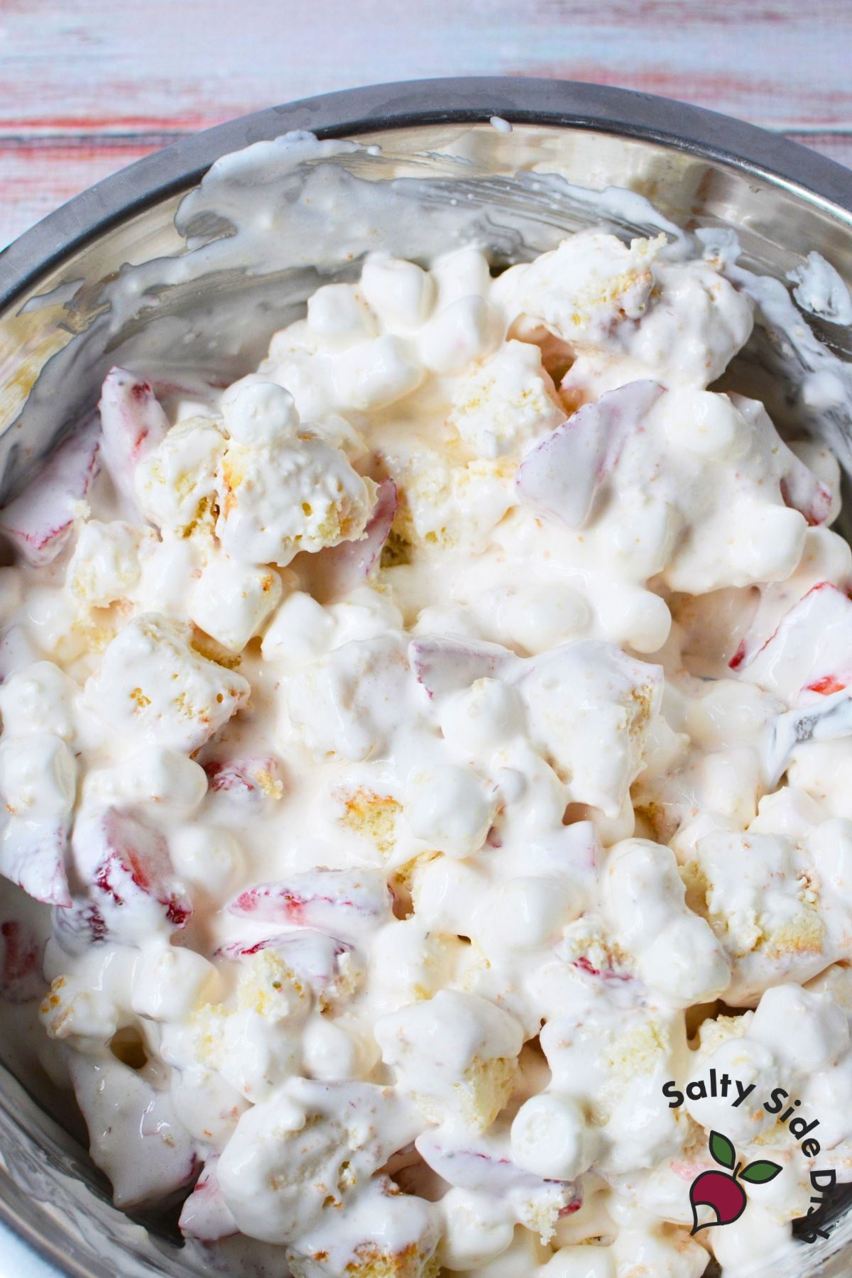 Strawberry shortcake fluff salad with pound cake, strawberries, mini marshmallows, and whipped topping in a mixing bowl