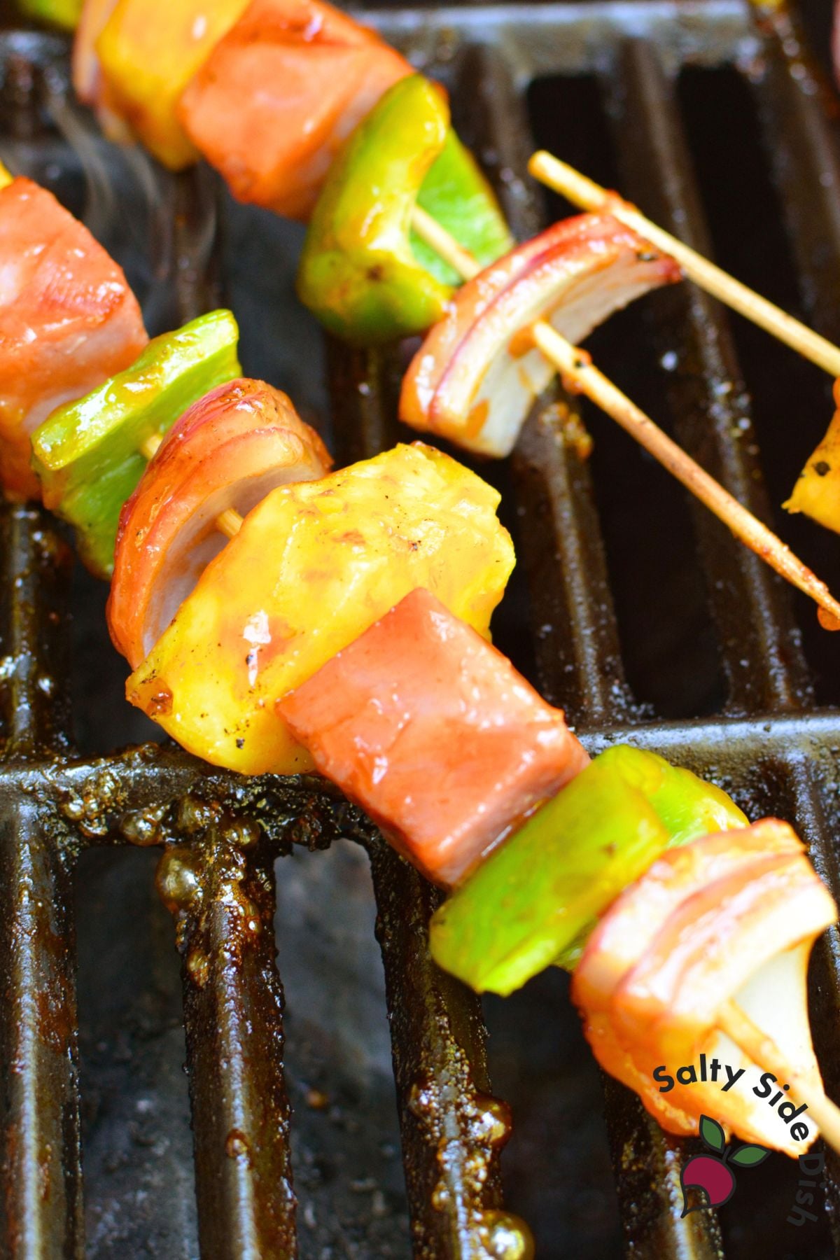 Ham and pineapple skewers grilling with green pepper and red onion