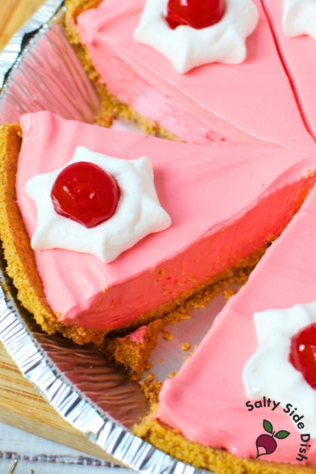 Homemade Kool Aid pie sliced in a graham cracker crust with whipped topping and cherries