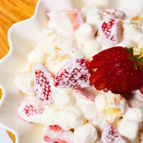 Creamy strawberry shortcake fluff salad served in a white bowl with fresh strawberries and pound cake pieces
