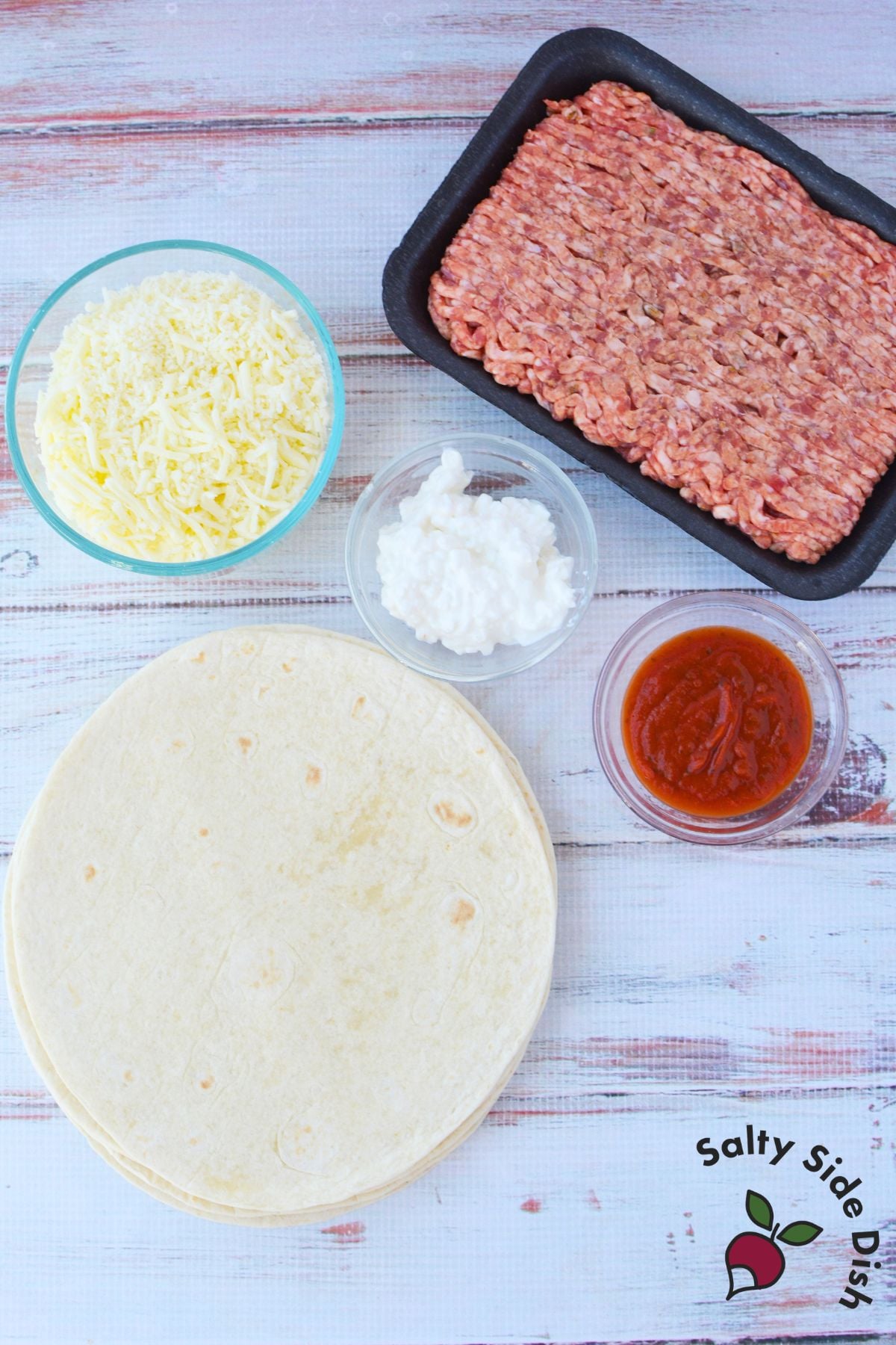 Ingredients for lasagna rolls with tortillas including Italian sausage, mozzarella, cottage cheese, and pasta sauce