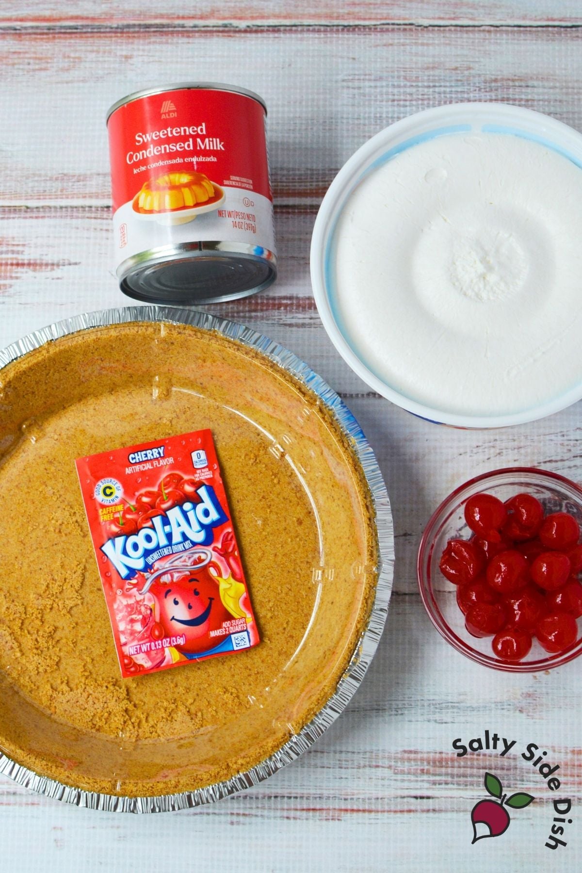 Kool Aid pie ingredients including cherry Kool-Aid, sweetened condensed milk, whipped topping, graham cracker crust, and cherries