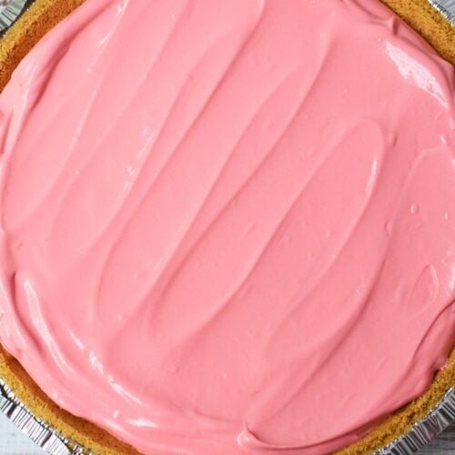 Cherry Kool Aid pie filling spread evenly in a graham cracker crust
