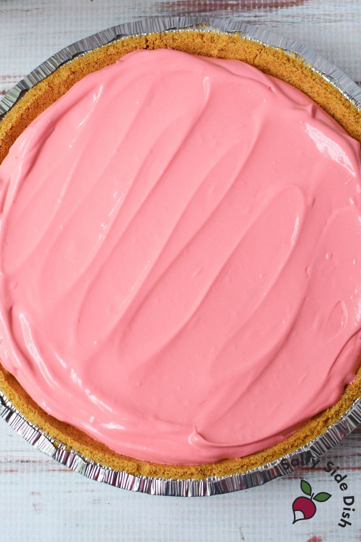 Cherry Kool Aid pie filling spread evenly in a graham cracker crust