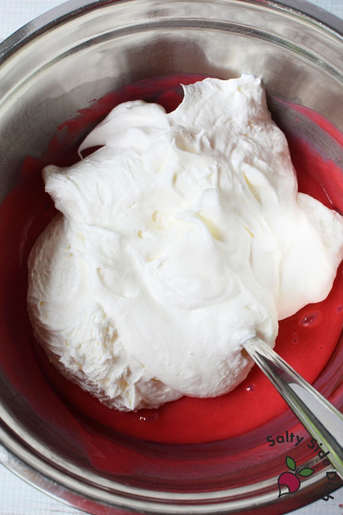 Whipped topping being folded into the cherry Kool Aid pie mixture