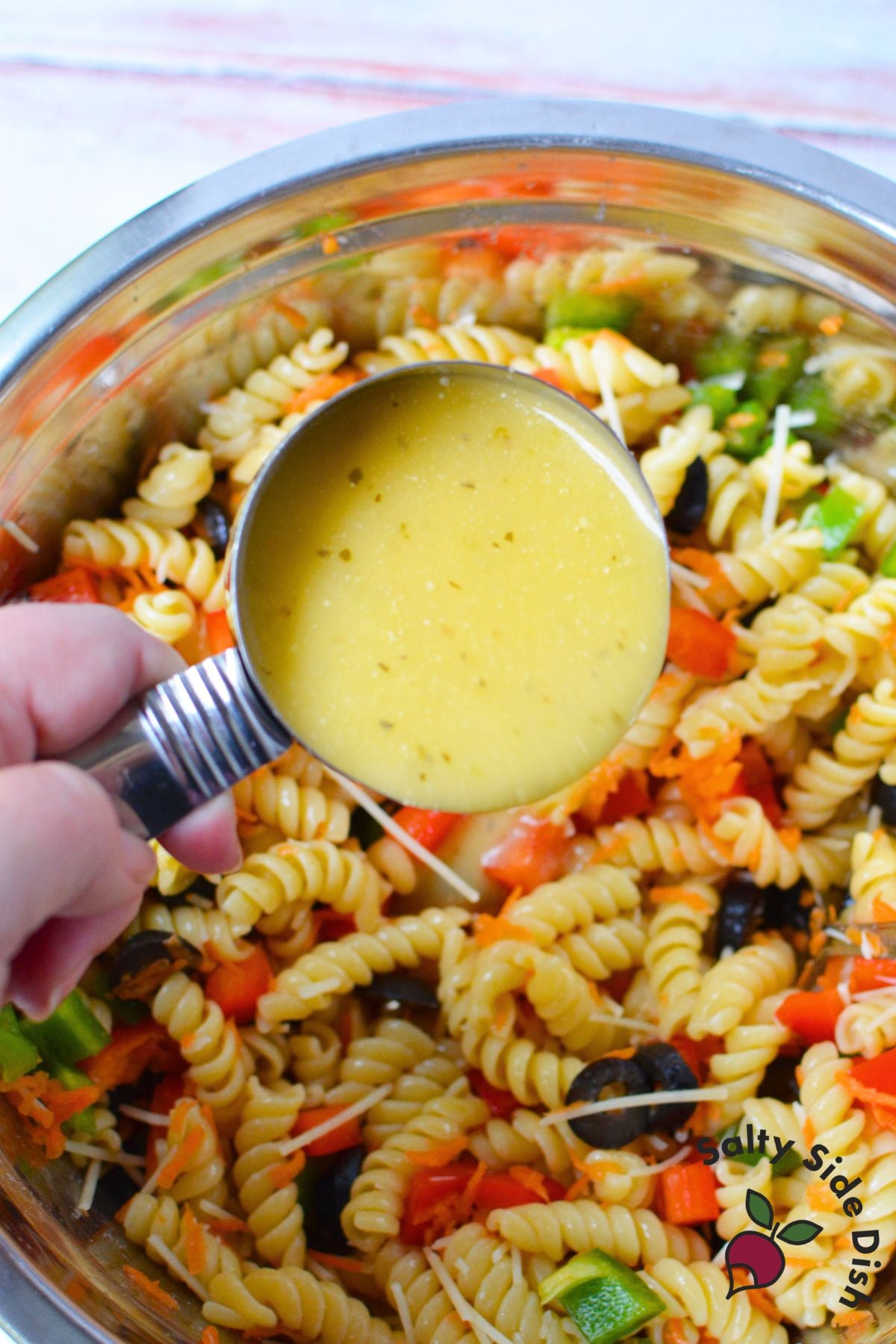 Olive Garden Signature Italian Dressing being poured over rotini pasta salad ingredients