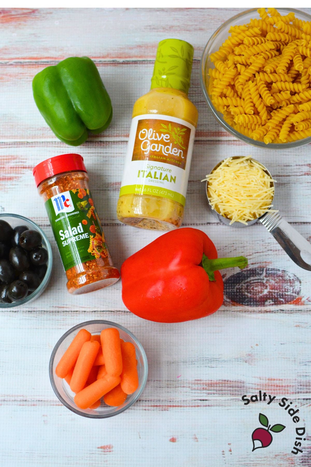 Ingredients for Olive Garden pasta salad including rotini, peppers, carrots, olives, Parmesan, and Italian dressing