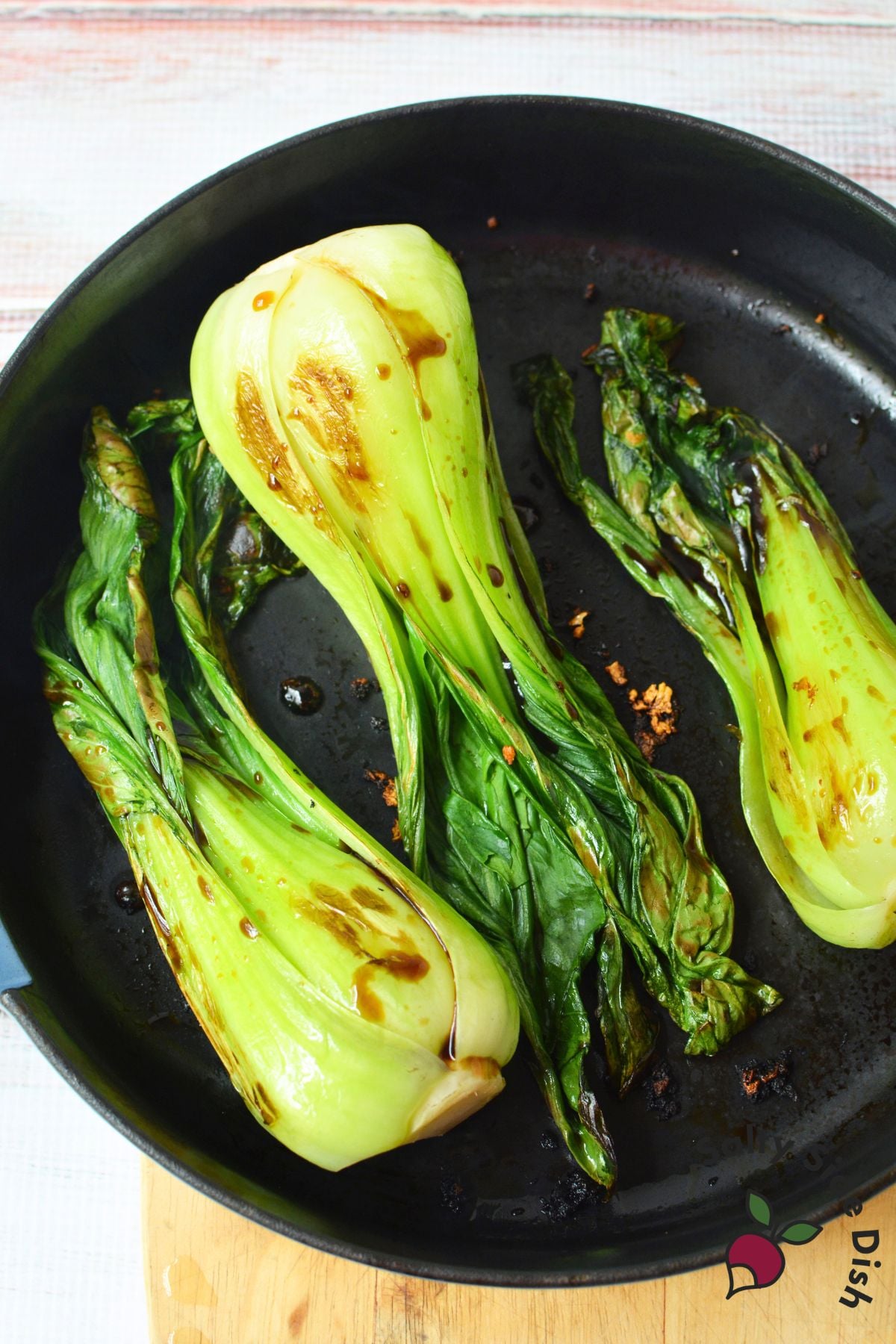 Sautéed bok choy with garlic, sesame seeds, and crushed red pepper served on a white platter