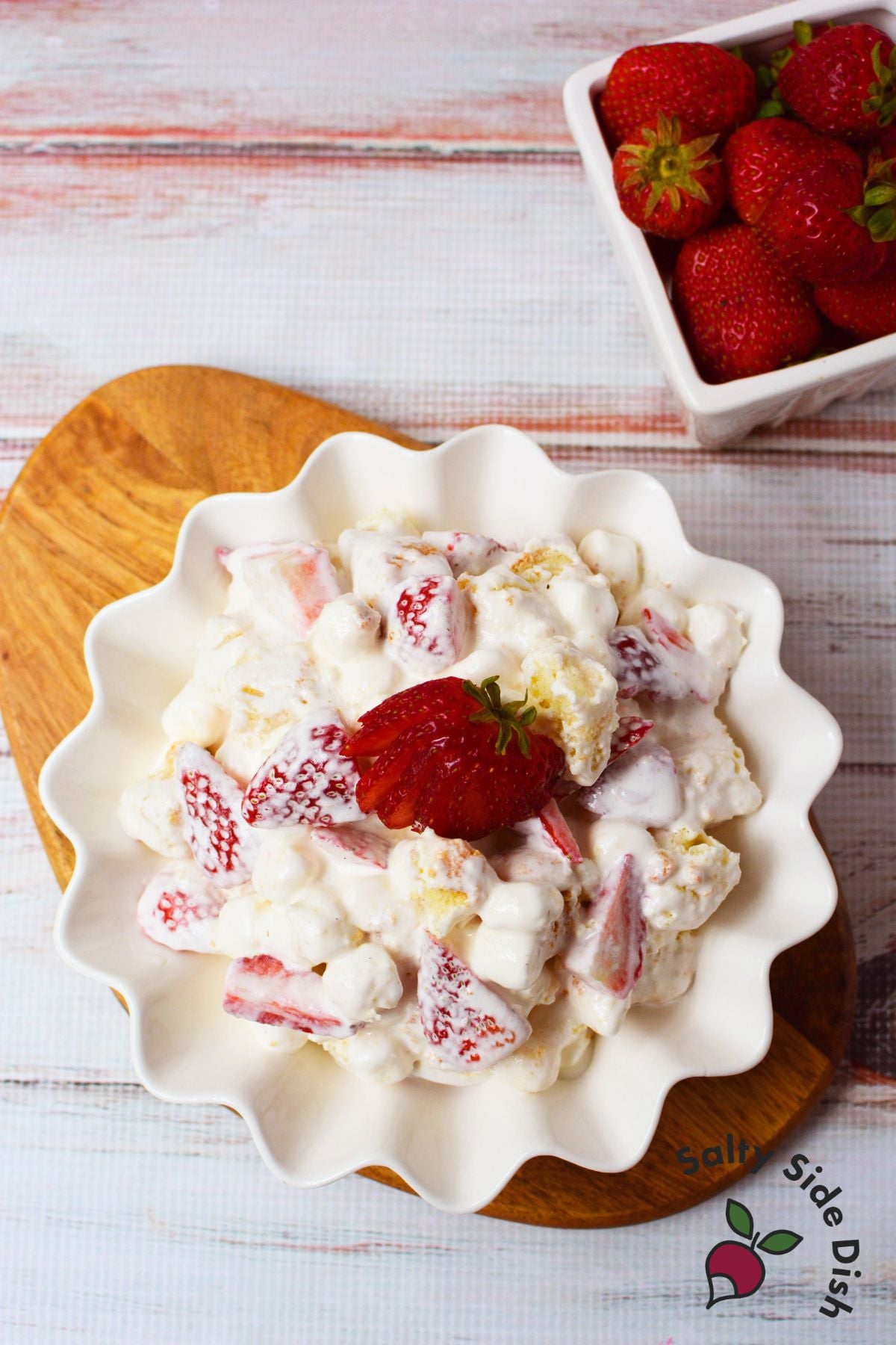 Bowl of strawberry shortcake fluff salad topped with a fresh strawberry