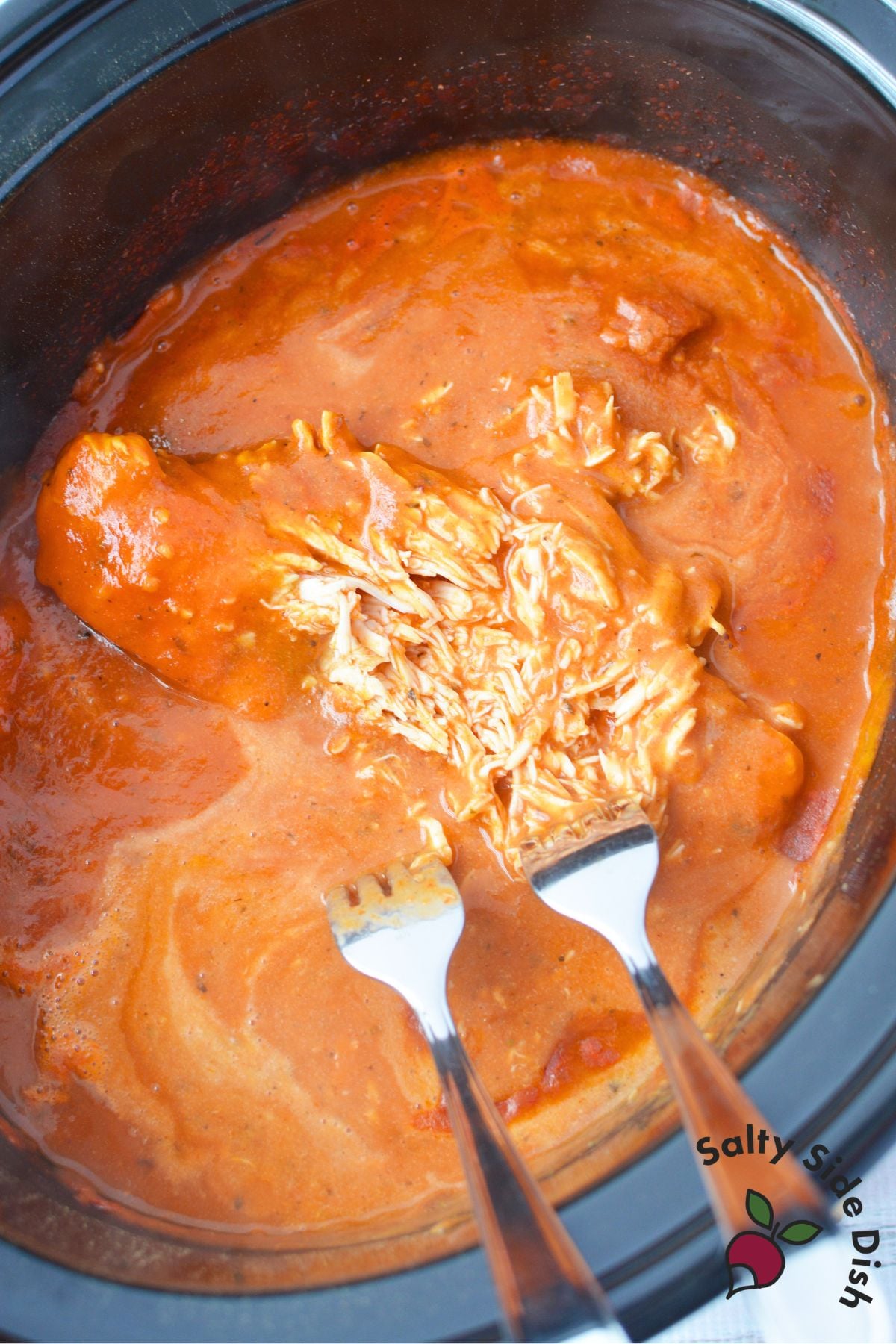 Shredding cooked chicken in creamy marinara and Alfredo pink sauce
