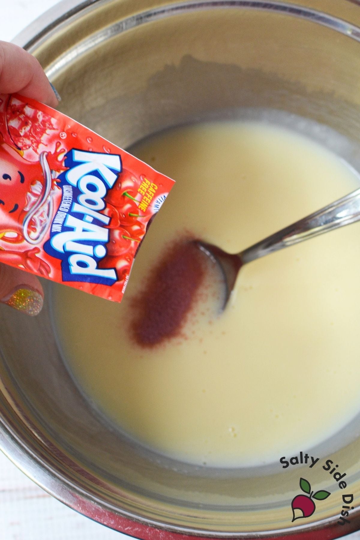 Cherry Kool-Aid drink mix being added to sweetened condensed milk for Kool Aid pie