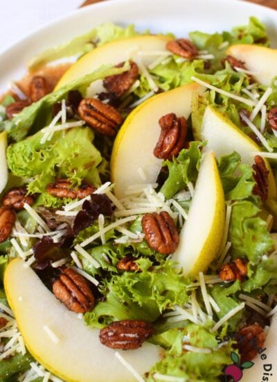 Fall pear salad with sliced pears, spiced pecans, Parmesan cheese, spring greens, and balsamic dressing