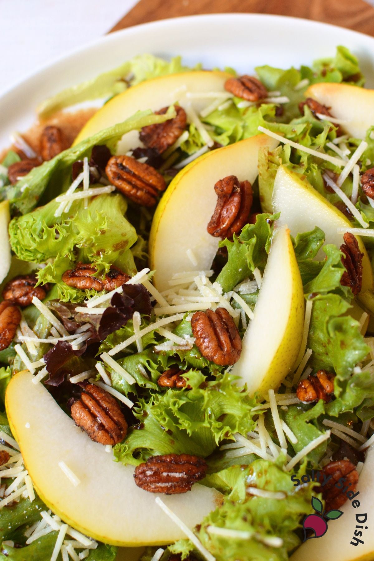 Fall pear salad with sliced pears, spiced pecans, Parmesan cheese, spring greens, and balsamic dressing