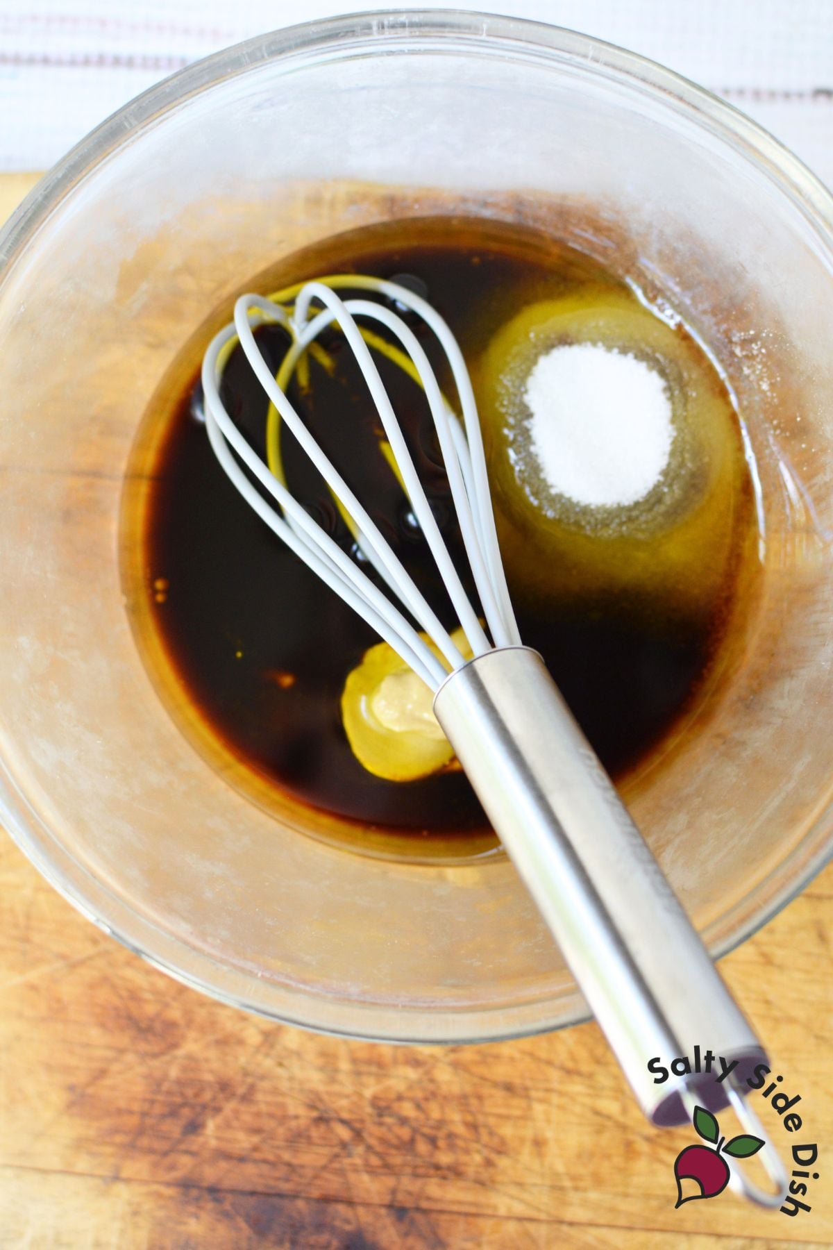 Homemade balsamic Dijon dressing ingredients in a glass bowl with whisk