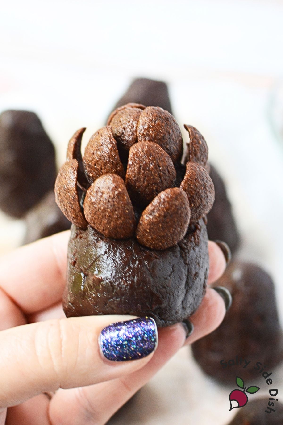 Chocolate cereal pieces being pressed into a shaped brownie to create the pinecone texture.