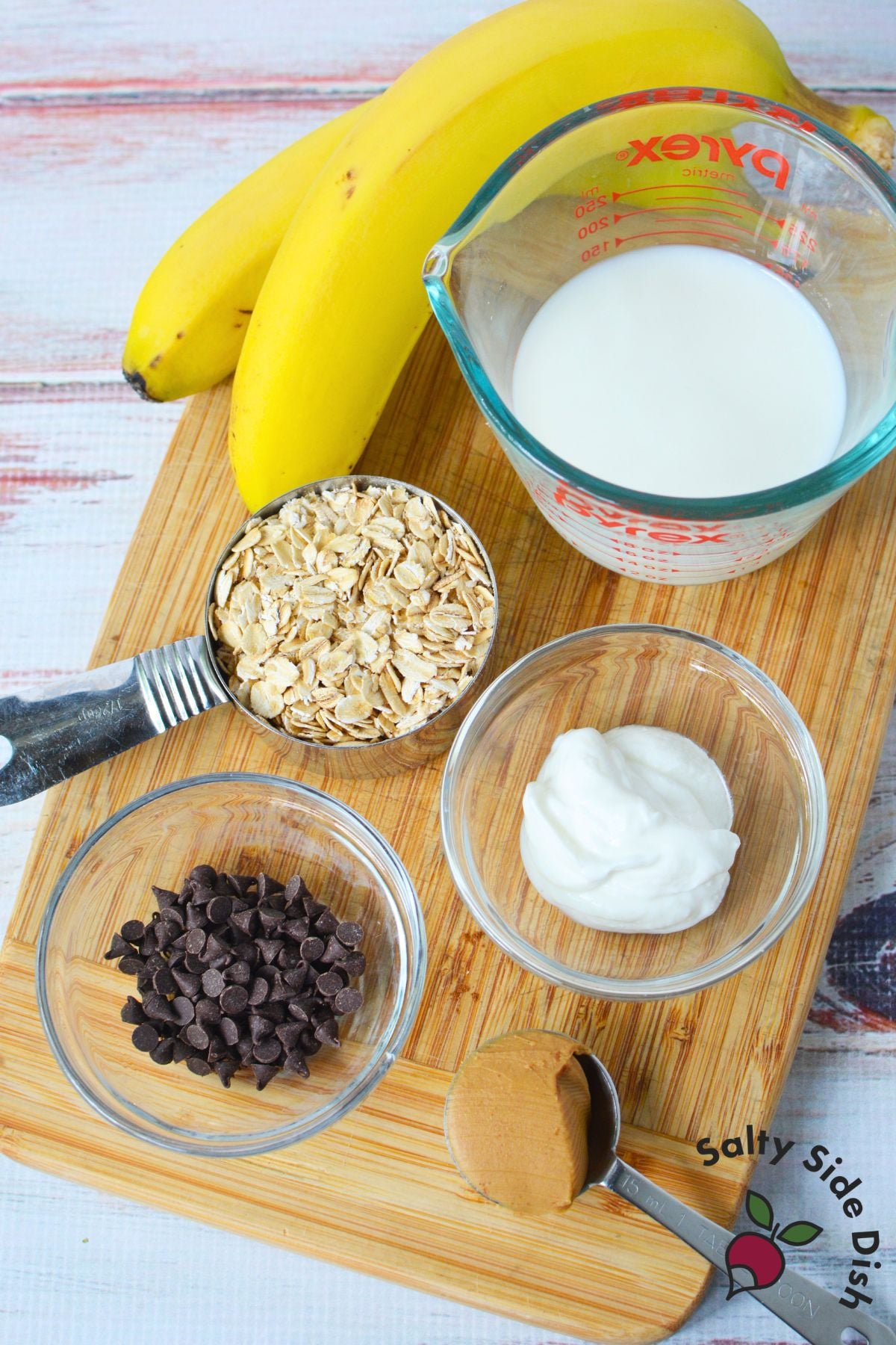 Ingredients for homemade overnight oats with rolled oats, milk, Greek yogurt, banana, peanut butter, and mini chocolate chips.