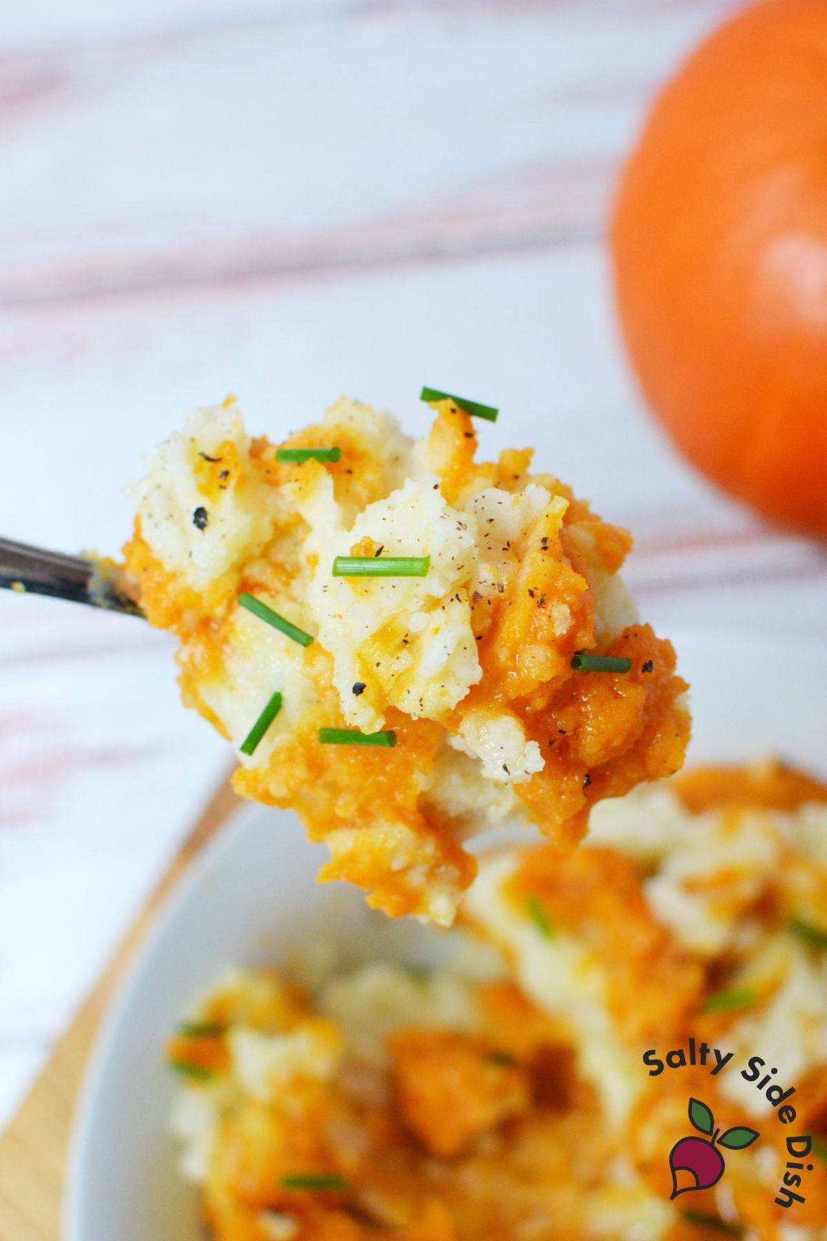 Forkful of pumpkin mashed potatoes with chives and black pepper