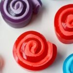 Colorful Jello roll ups in red, blue, and purple with marshmallow swirl centers