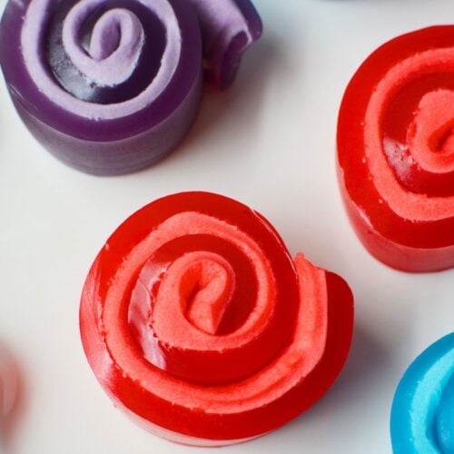 Colorful Jello roll ups in red, blue, and purple with marshmallow swirl centers