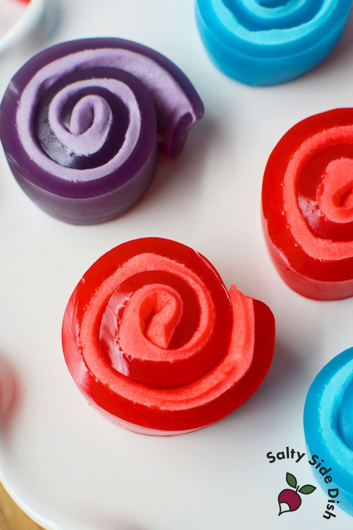 Colorful Jello roll ups in red, blue, and purple with marshmallow swirl centers