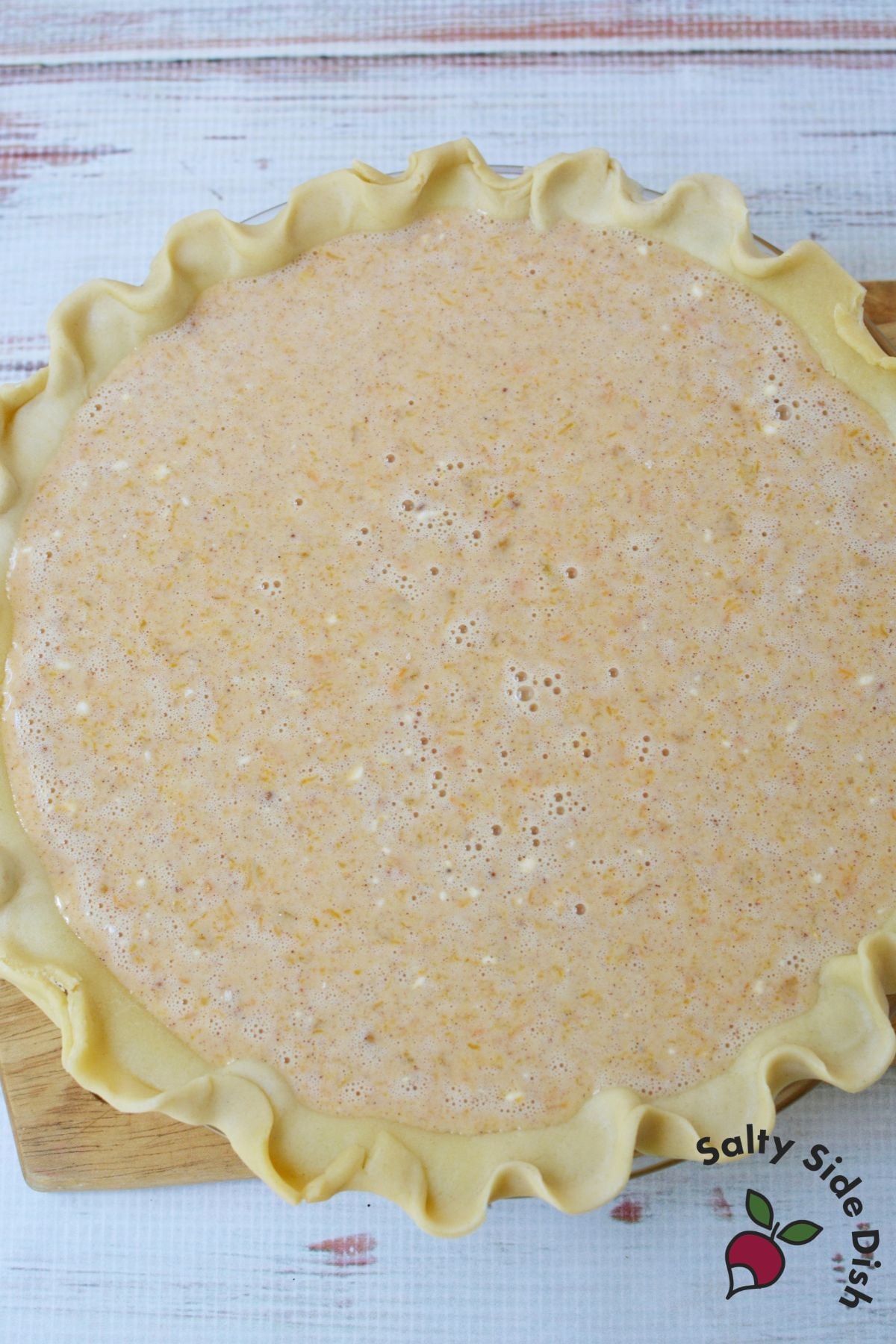 Unbaked butternut squash and sweet potato pie filling in a prepared pie crust before baking.