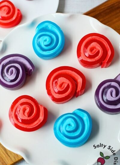 Red Jello marshmallow roll up held up to show the spiral pinwheel shape