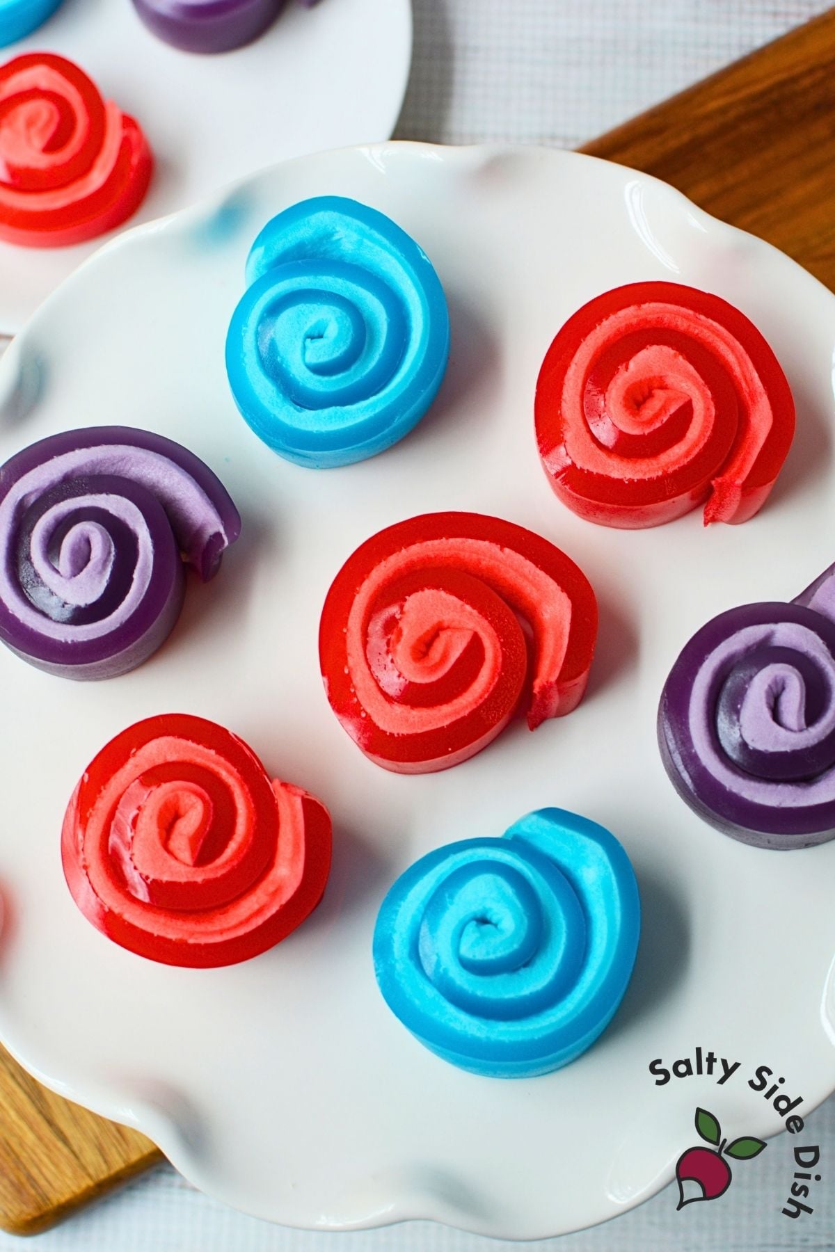 Red Jello marshmallow roll up held up to show the spiral pinwheel shape