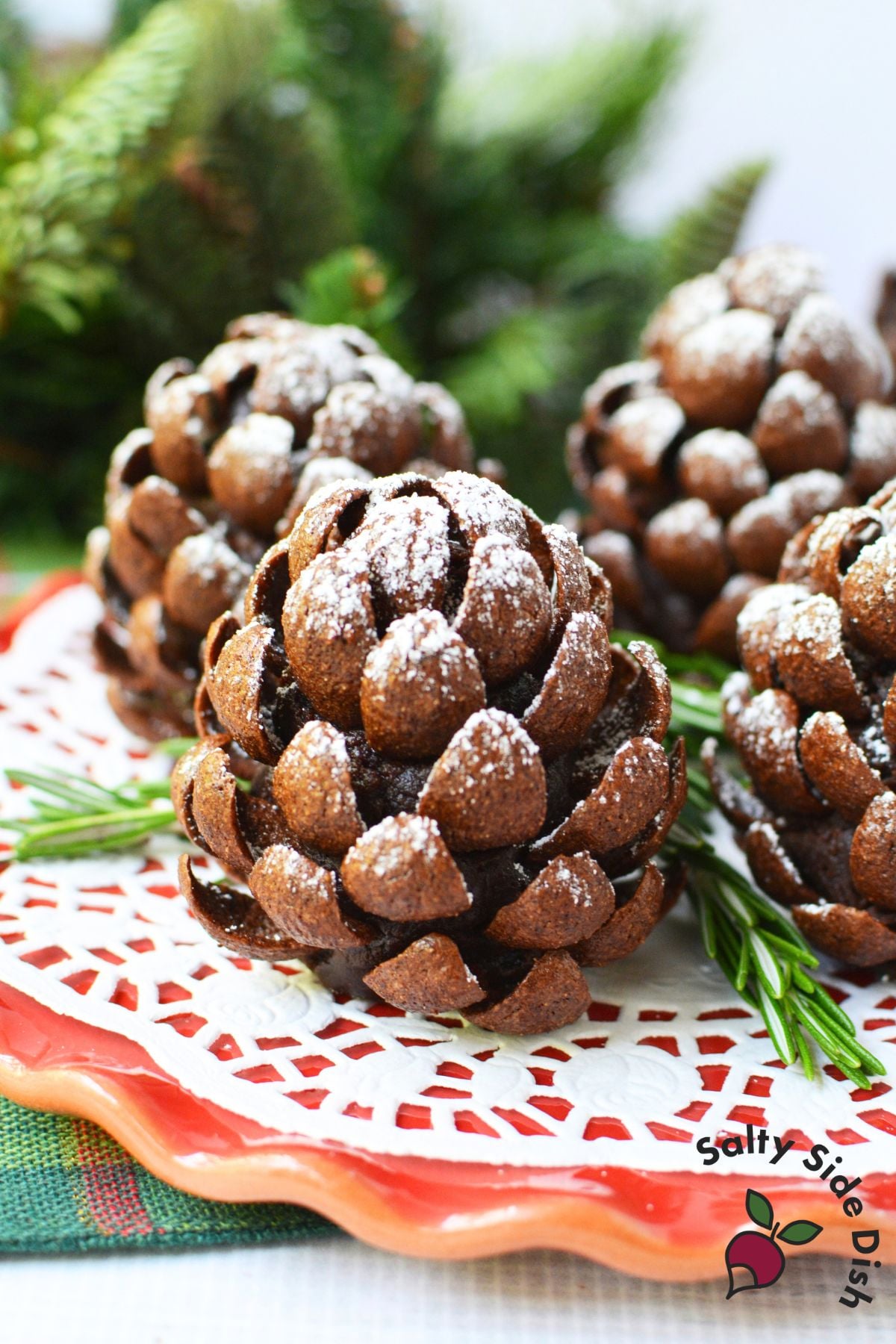 Pinecone brownies dusted with powdered sugar and arranged with rosemary on a holiday platter.