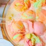 Rainbow sherbet punch in a glass bowl with colorful scoops of sherbet floating on top