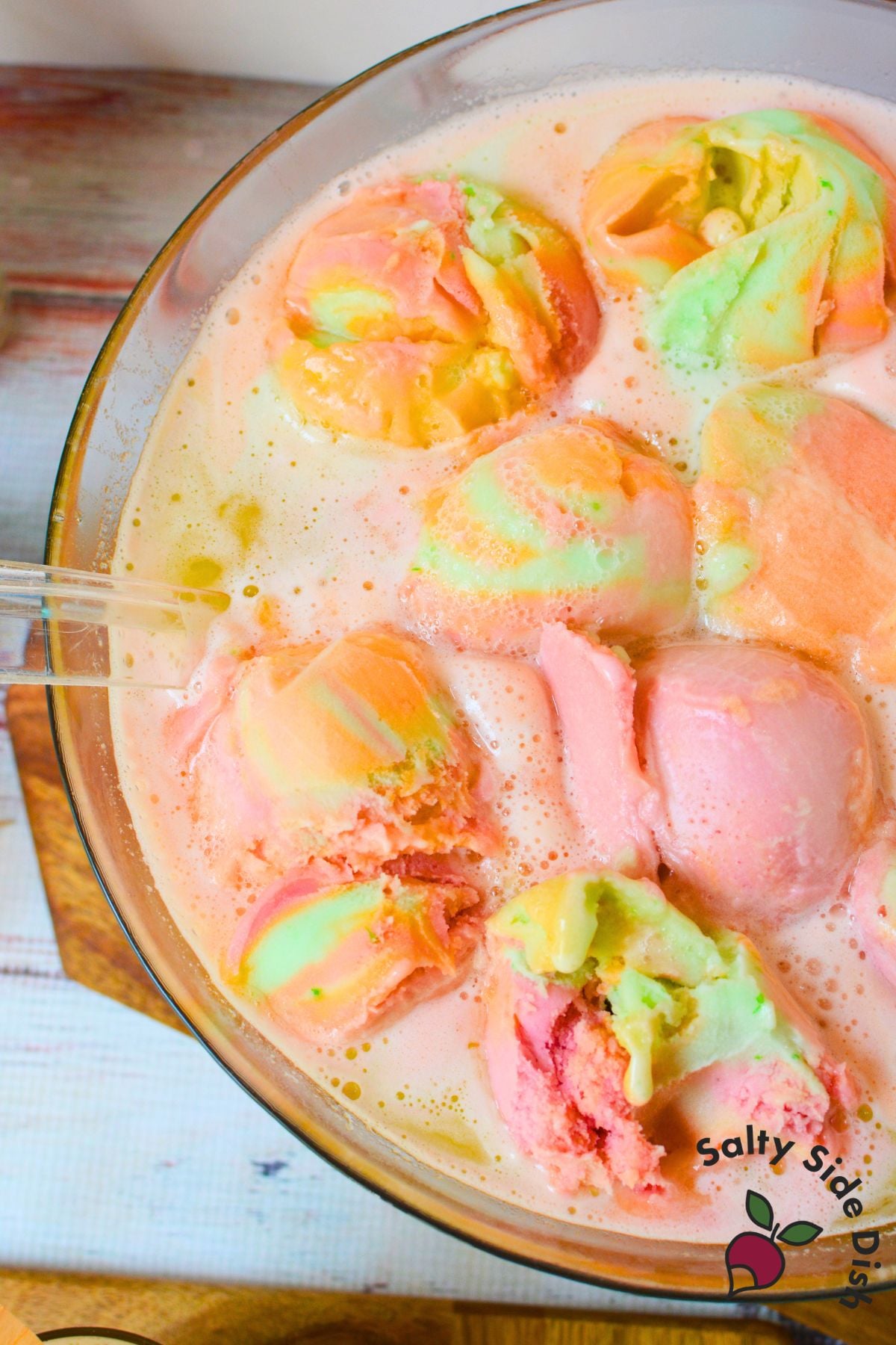 Rainbow sherbet punch in a glass bowl with colorful scoops of sherbet floating on top